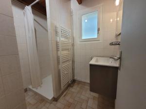 un bagno con doccia, lavandino e finestra di Maison proche viaduc de Garabit a Loubaresse