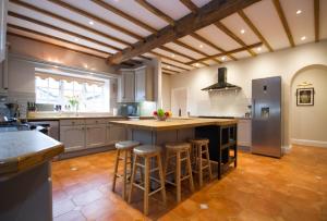 a large kitchen with a large island with bar stools at Greens Norton House in Towcester