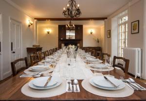 a long table with white plates and silverware on it at Greens Norton House in Towcester