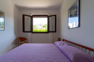 Un dormitorio con una cama morada y una ventana. en Villa Dalila by BarbarHouse, en Torre Inserraglio