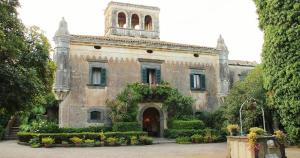 ein altes Gebäude mit einem Turm darüber in der Unterkunft NEW Casa Vacanze 23 in Fiumefreddo di Sicilia