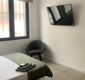 - une chambre avec une chaise et une télévision murale dans l'établissement Habitación en Playa Malvarrosa con baño privado -No AC-, à Valence