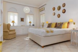 1 dormitorio blanco con 1 cama grande y 1 silla en Naxos Beach Front Villa ''Moments'' en Ambrami
