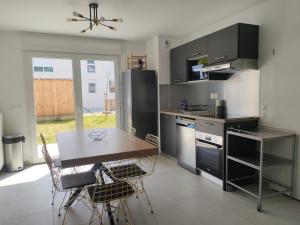 uma cozinha com uma mesa e algumas cadeiras e um frigorífico em Maison au Pegasus Bridge & Proche Plage em Bénouville