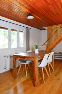 納瓦塞拉達的住宿－NIMA Navacerrada，一间带木桌和白色椅子的用餐室