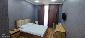 a bedroom with a bed and a desk and a window at Very Well Guest House in Baku