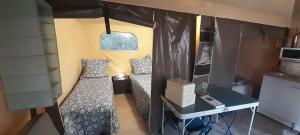 Cette petite chambre comprend un lit et un bureau. dans l'établissement Logement Lodge au cœur de la Manade, à Aigues-Mortes