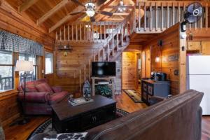 a living room with a staircase in a log cabin at Mountain Time Cabin, Hot tub, Fire Pit, Fireplace in Blue Ridge