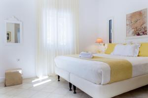 een witte slaapkamer met een groot bed met gele accenten bij Naxos Beach Front Villa ''Moments'' in Ambrami