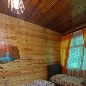 Pokój z drewnianą ścianą, łóżkiem i oknem w obiekcie AYDER Nazlı çiçek apart w mieście Ayder Yaylasi
