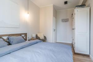 a bedroom with a bed with blue sheets and a door at Apartament przy Stajennej in Gdańsk