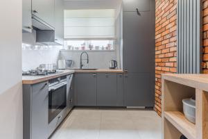 a kitchen with gray cabinets and a brick wall at Apartament przy Stajennej in Gdańsk