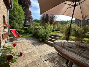 a patio with a wooden table and an umbrella at La Faironnière in Hamoir