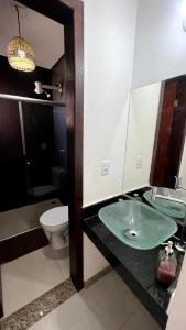 een badkamer met een wastafel, een toilet en een spiegel bij Porto Ville Home - AP 2 quartos in Porto Seguro