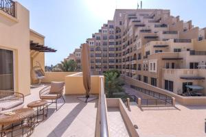 a balcony with chairs and tables and a large building at Sensational 1BR in Bab Al Bahar with Beach Access in Ras al Khaimah