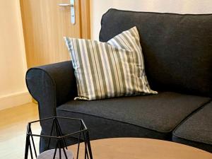 a black couch with a striped pillow on it at Ferienwohnung Fuldaufer in Melsungen