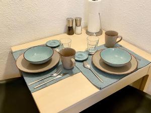 una mesa con platos, tazas y utensilios. en Ferienwohnung Fuldaufer, en Melsungen