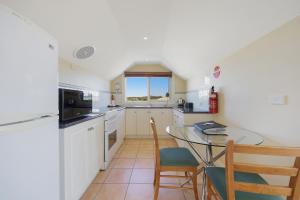 a kitchen with a table and chairs and a window at Logans Beach Whale Nursery Apartments - The Loft in Warrnambool