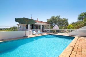 einen Pool mit Sonnenschirm und ein Haus in der Unterkunft Casa Kuito in Estói