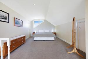 a white bedroom with a bed and a window at Logans Beach Whale Nursery Apartments - The Loft in Warrnambool