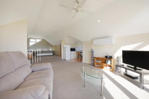 a living room with a couch and a flat screen tv at Logans Beach Whale Nursery Apartments - The Loft in Warrnambool