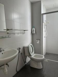 a white bathroom with a toilet and a sink at Mr.J Homestay in Taiping