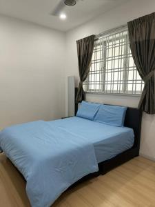 una camera da letto con un letto con lenzuola blu e una finestra di Mr.J Homestay a Taiping