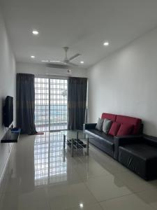 ein Wohnzimmer mit einem schwarzen Sofa und einem TV in der Unterkunft Mr.J Homestay in Taiping