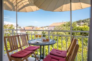 un balcone con tavolo, 2 sedie e ombrellone di Apartments Karisima a Korčula