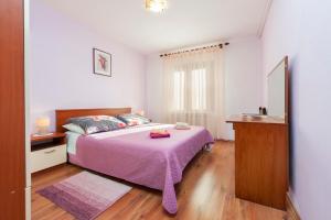 1 dormitorio con 1 cama con manta morada y espejo en Apartments Adria en Rovinj