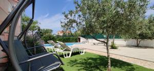 a backyard with a pool and chairs and a tree at Relax to the max with the sea view in Medulin