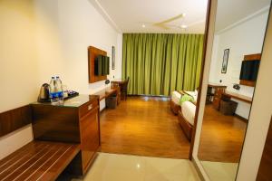 Habitación de hotel con cama y sala de estar. en HOTEL CEASAR PALACE, en Kottayam