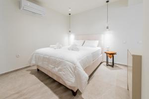 a white bedroom with a large bed and a table at Gemela AllstarBoutique in Aegina A in Aegina Town