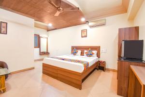 um quarto com uma cama e uma televisão de ecrã plano em FabHotel Shreeyash Residency em Pune