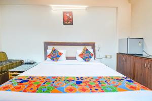 um quarto com uma cama com um edredão colorido em FabHotel Shreeyash Residency em Pune