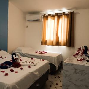 2 camas en una habitación con rosas en el suelo en Pousada Ponta Negra, en Natal