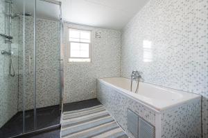 een badkamer met een bad en een glazen douche bij 79, Ruime chalet aan de Kampina in Oisterwijk