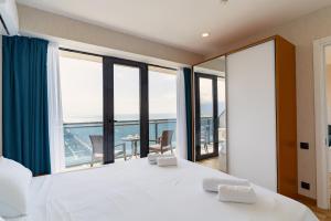 een slaapkamer met een groot wit bed en grote ramen bij Orbi Beach 33 floor with great view in Batoemi