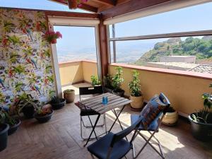 un balcone con tavolo, sedie e piante in vaso. di Enna Cerere a Enna