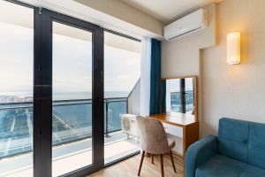 een kamer met een blauwe bank, een bureau en een raam bij Orbi Beach 33 floor with great view in Batoemi