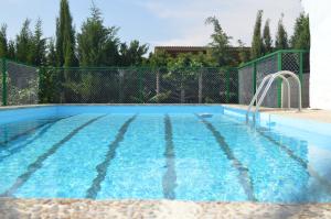 a swimming pool with blue water in a fence at MASIA ESTORACH in L'Aldea