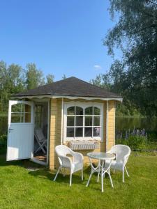 a small shed with a table and chairs in the grass at Jokiranta in Kouvola