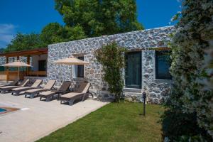 a group of chairs and umbrellas in front of a stone building at Eroğlu Villas in Fethiye