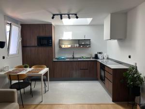 a kitchen with wooden cabinets and a table with chairs at Bierzo Habita Apartments in Ponferrada