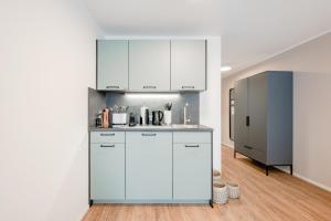 a kitchen with white cabinets and a refrigerator at limehome Metzingen Wilhelmstr in Metzingen