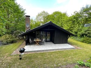 un cobertizo negro con una mesa en el césped en Ferienhaus Kleine Auszeit in der Natur mit Kamin, Yogamatten, schöne Küche en Extertal