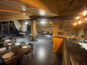 LE CHALET MONT HOTEL AND RESTAURANT في Chorwoq: مطعم بطاولات وكراسي وشخص في الخلفية