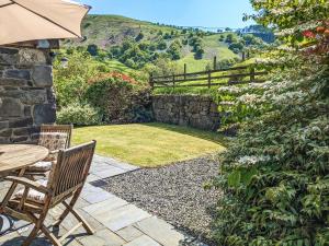 a patio with a table and chairs and a stone wall at Yr Efail - Hw7387 in Llanymawddwy