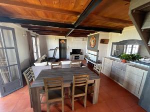 cocina y comedor con mesa de madera y sillas en La maison des camélias, en Le Tampon