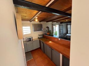 cocina con armarios grises y techo de madera en La maison des camélias, en Le Tampon